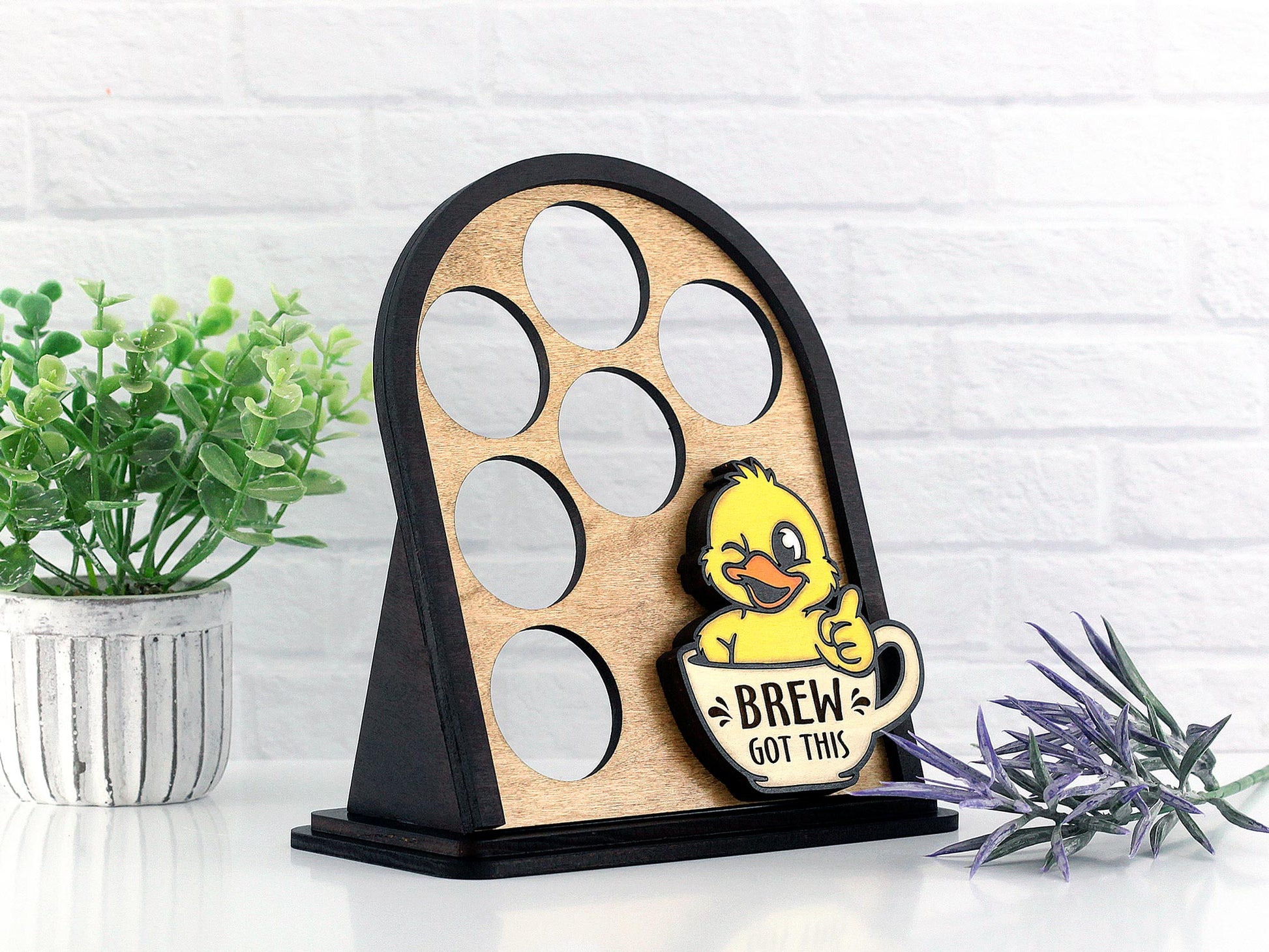 Wooden coffee pod display with a cute duck design on a white surface with plants.