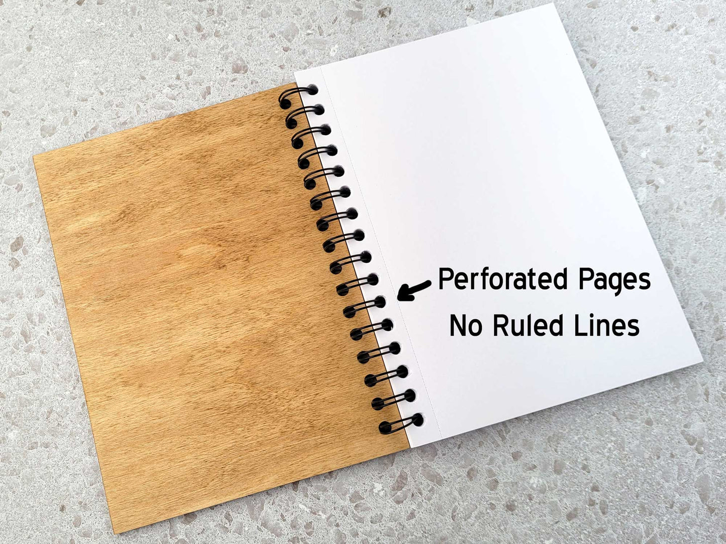 Journal with wooden cover and white pages on a gray surface, labeled 'Perforated Pages No Ruled Lines'.