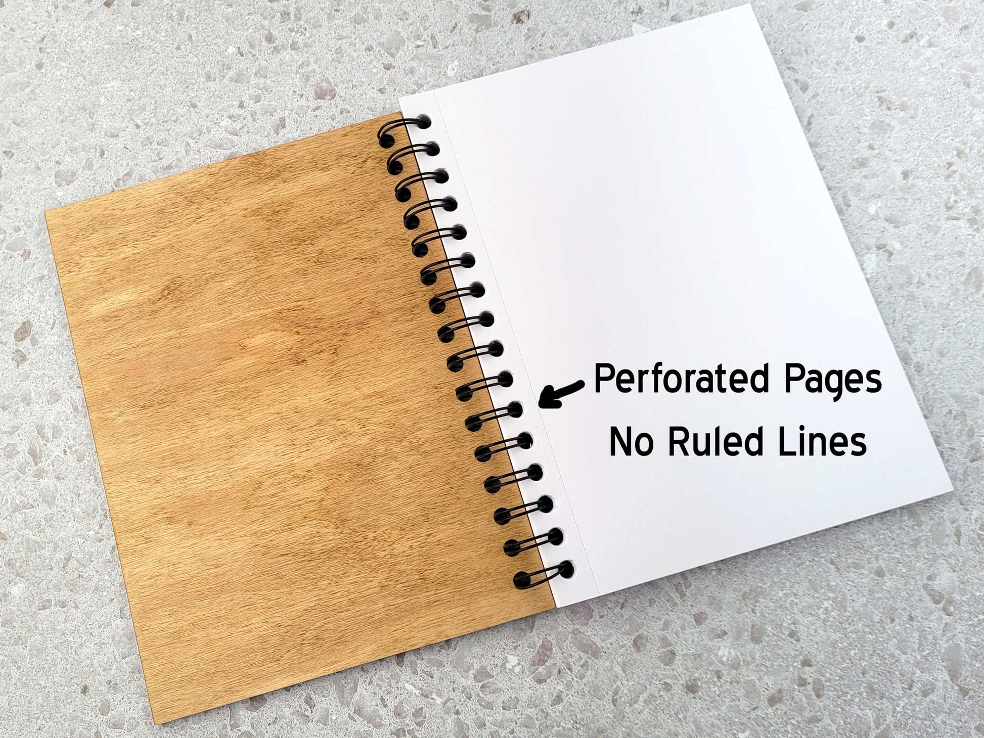 Journal with wooden cover and white pages on a gray surface, labeled 'Perforated Pages No Ruled Lines'.