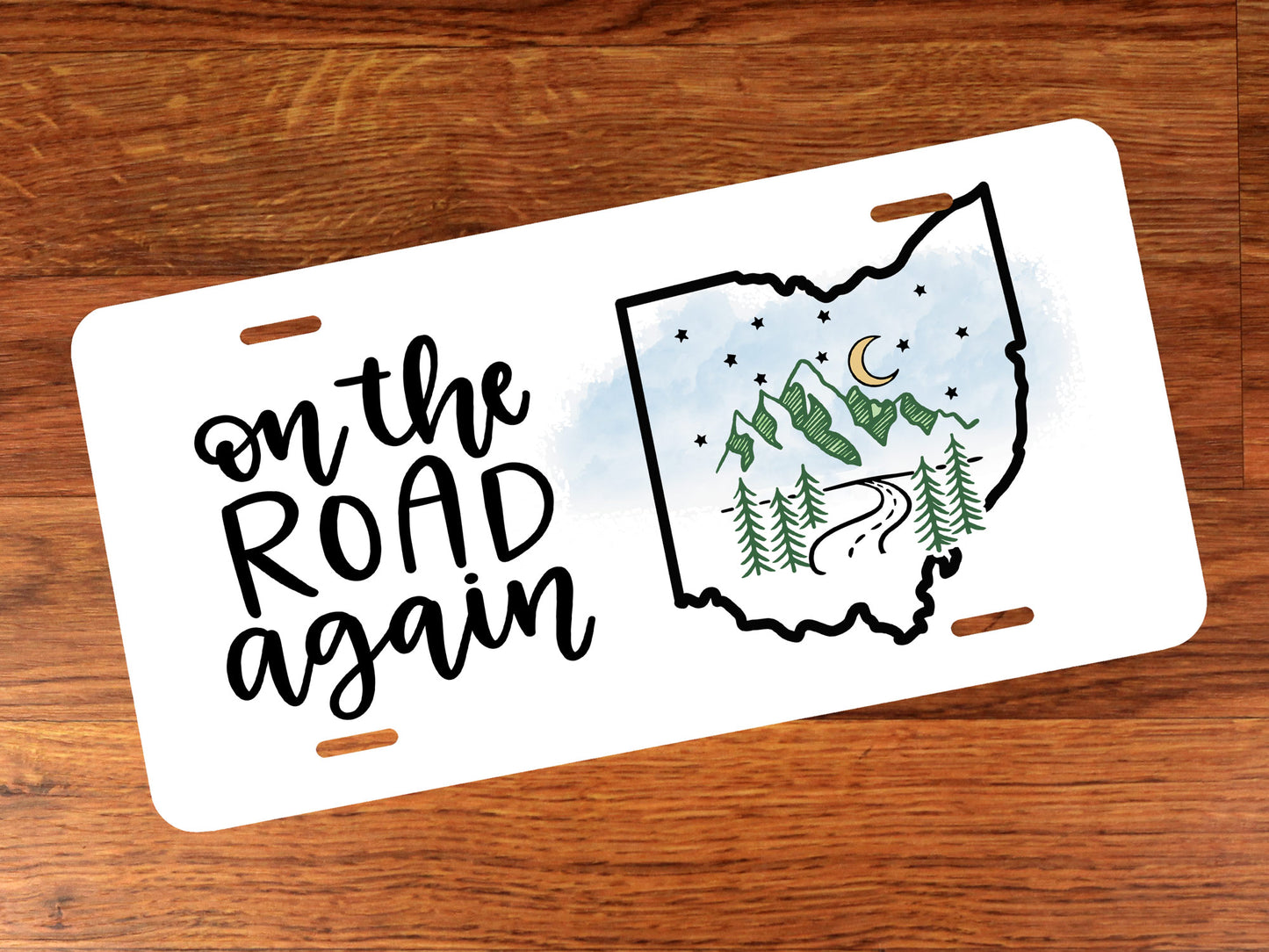 License plate with 'on the road again' text and Ohio outline design on a wooden surface