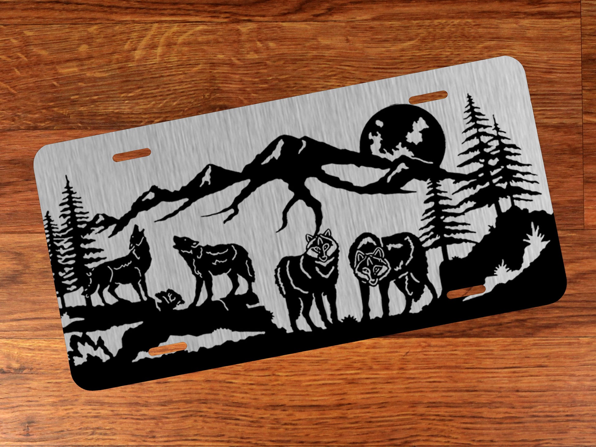 Decorative license plate with wolf and mountain design on silver against a wood background